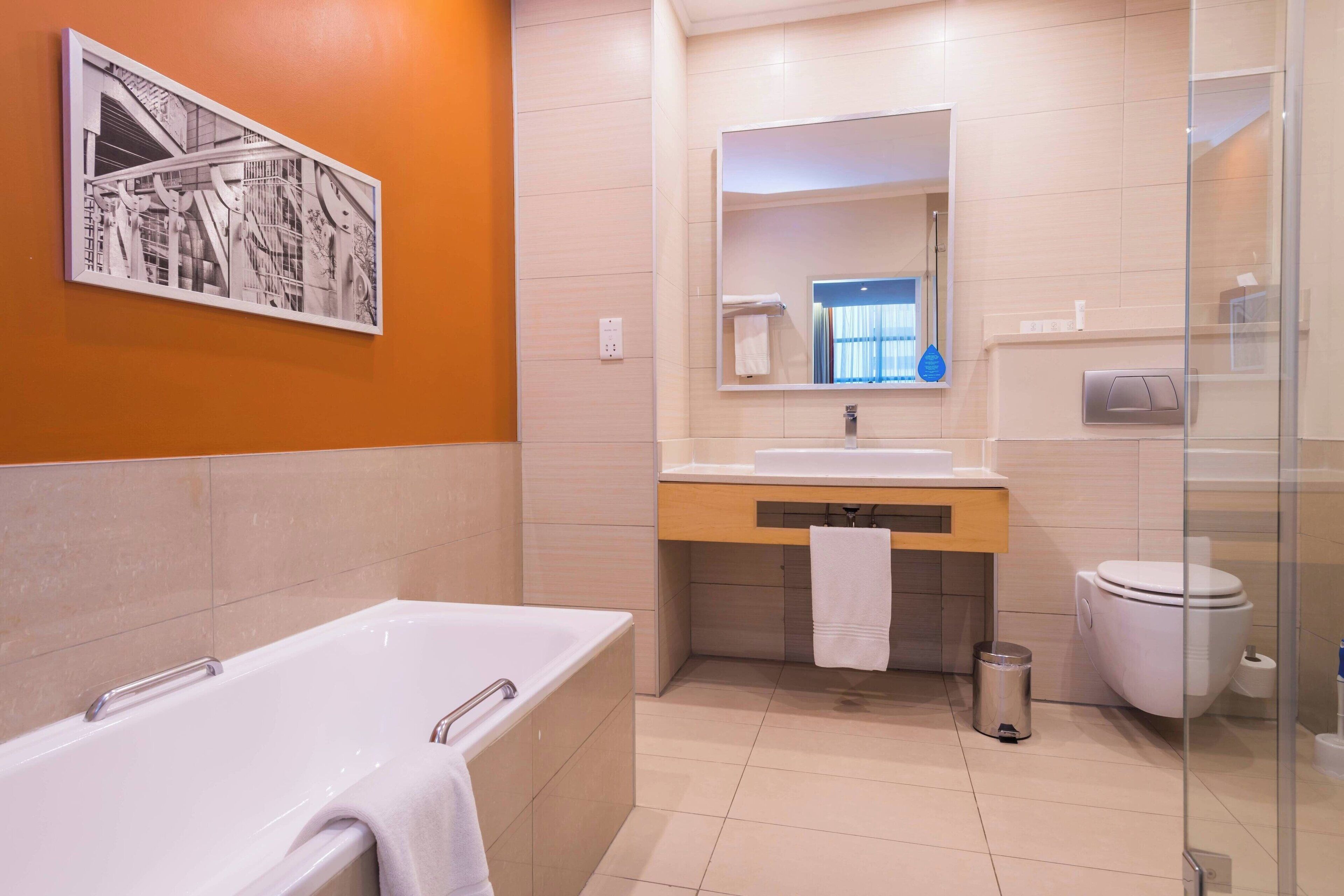 Un bagno moderno con vasca, lavandino, water e box doccia in vetro.