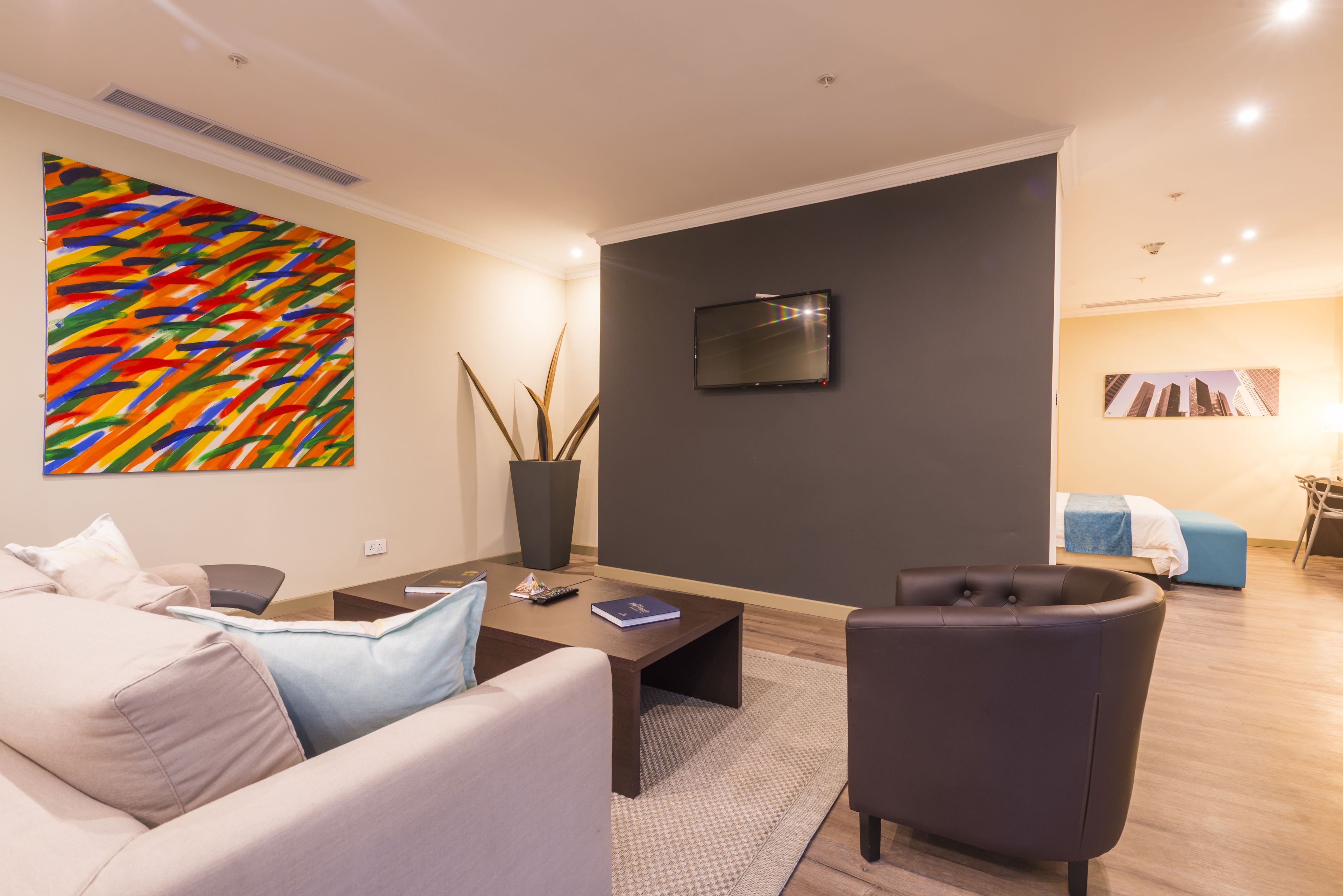 A modern living room with a sofa, a coffee table, a TV, and a colorful abstract painting.