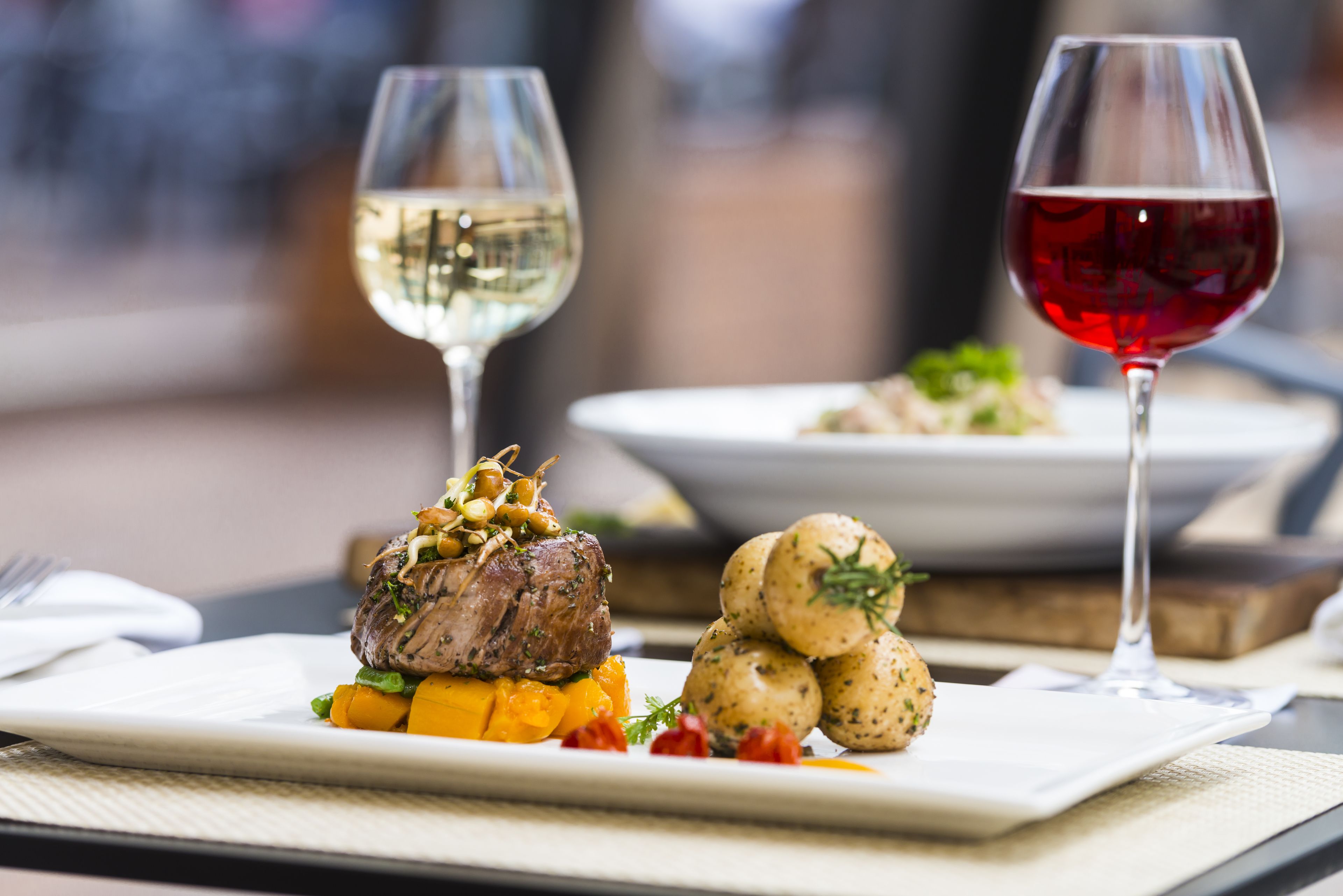 Une table à manger avec une assiette de nourriture, deux verres à vin et une serviette.
