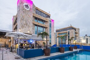 Ein Hotel mit Poolbereich, Außenbereich zum Sitzen und einer Bar.