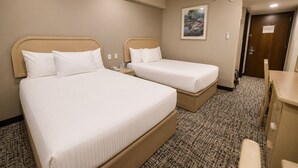 Une chambre d’hôtel avec deux lits, un bureau, une chaise, un tableau au mur et une porte.