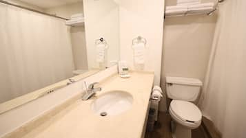 Un baño con lavamanos, espejo, inodoro y perchero para toallas.