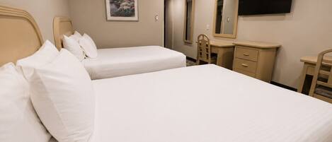 A hotel room with two beds, a bedside table, a dresser, a mirror, and a TV mounted on the wall.