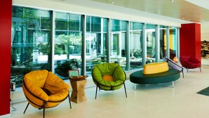 A modern lobby with large windows, a reception desk, and colorful seating areas. - Kristal (Zane)