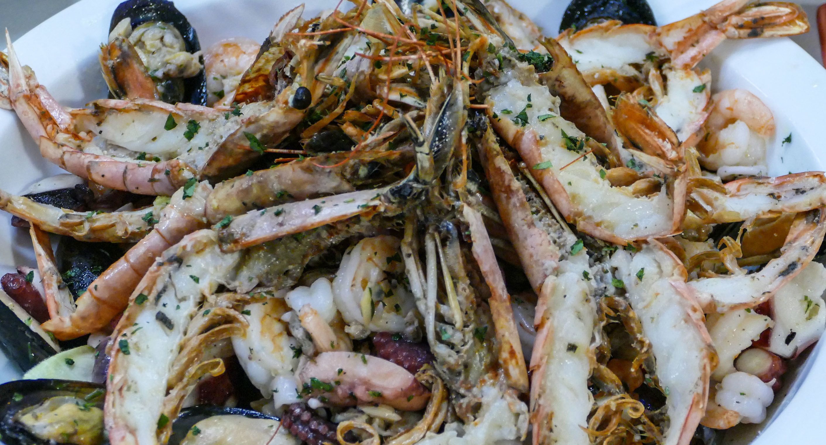 A seafood platter with various shellfish, including shrimp and mussels, garnished with herbs.