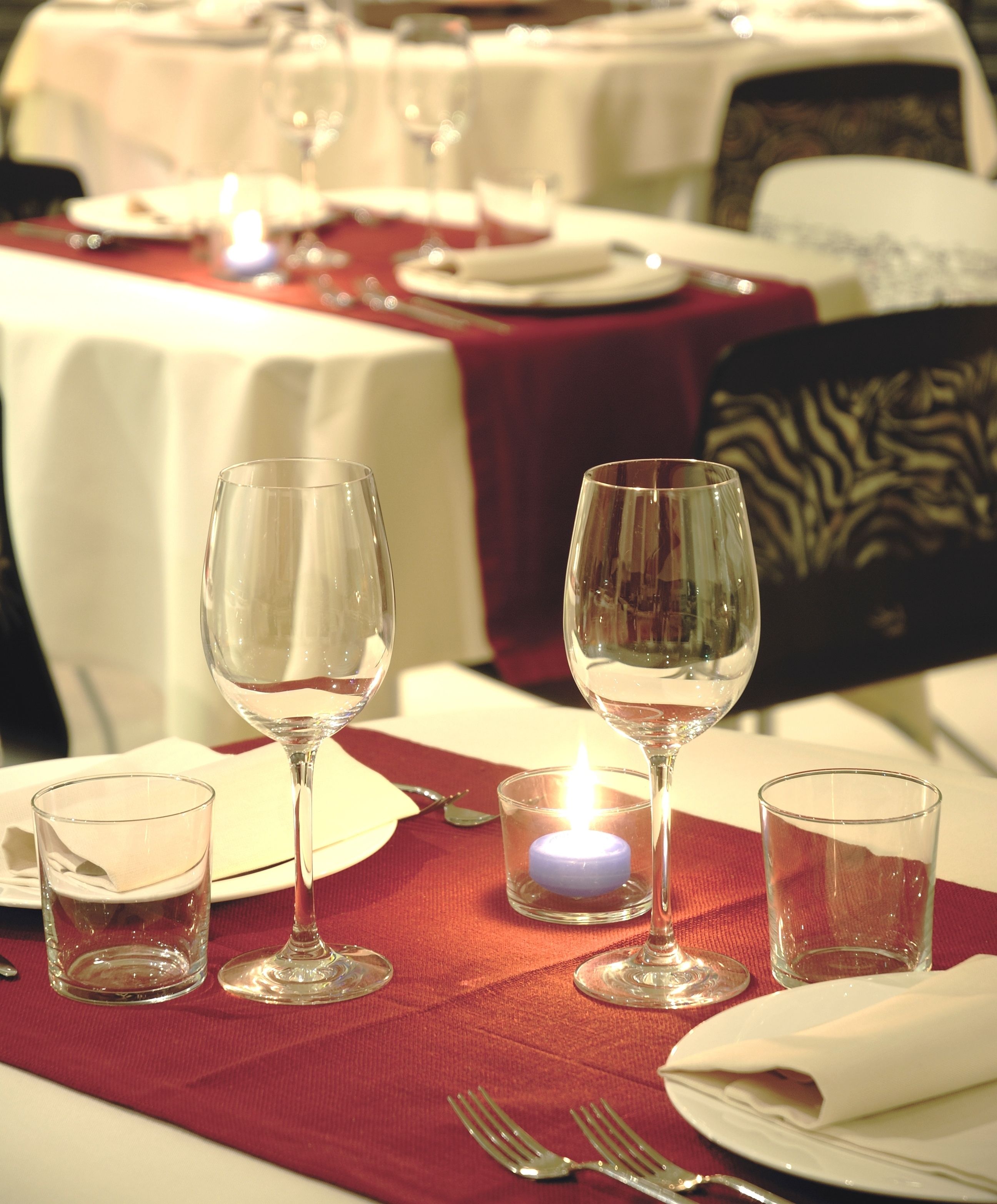 A dining table set with wine glasses, a candle, and cutlery.