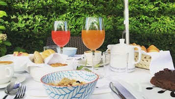 Ein Tisch ist mit Frühstücksartikeln gedeckt, darunter Croissants, eine Schüssel mit Müsli, Kaffee und zwei Gläser Saft.