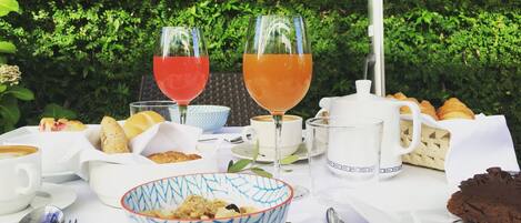 Une table dressée avec des aliments pour le petit-déjeuner, notamment des croissants, un bol de céréales, du café et deux verres de jus de fruits.