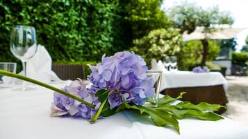 A table with a glass of water, a glass of wine, and a bouquet of purple flowers.