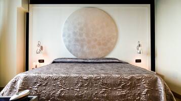 Un dormitorio moderno con un gran adorno circular en la pared, un edredón estampado y lámparas de noche.