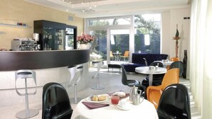 A modern cafe with a bar area, seating, and a view of the outdoors. - Kristal (Zane)