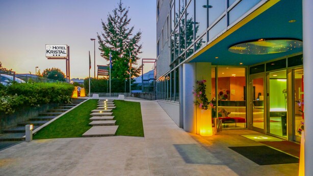 A hotel entrance with a sign reading "Hotel Kristal," a well-lit pathway leading to the entrance, and a modern building facade. - Kristal (Zane)