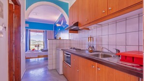 A modern kitchen with wooden cabinets, a stainless steel sink, and a red drying rack. - Kleopatra Studios (Zakynthos)