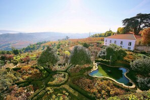 Un bâtiment blanc, surmonté d’un toit rouge, est entouré d’un jardin bien entretenu, agrémenté d’un bassin et de divers arbres.