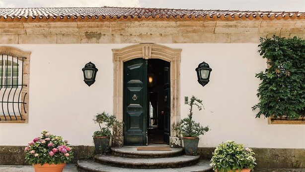 Een gebouw met een pannendak, een groene deur en twee wandlampen.