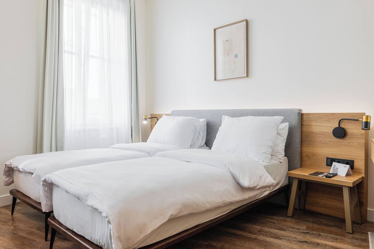 A double bed with a wooden frame, a bedside table with a lamp, and a framed picture on the wall.