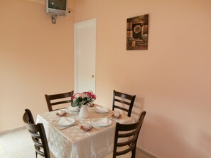A dining table set for four with a white tablecloth, floral centerpiece, and wooden chairs.