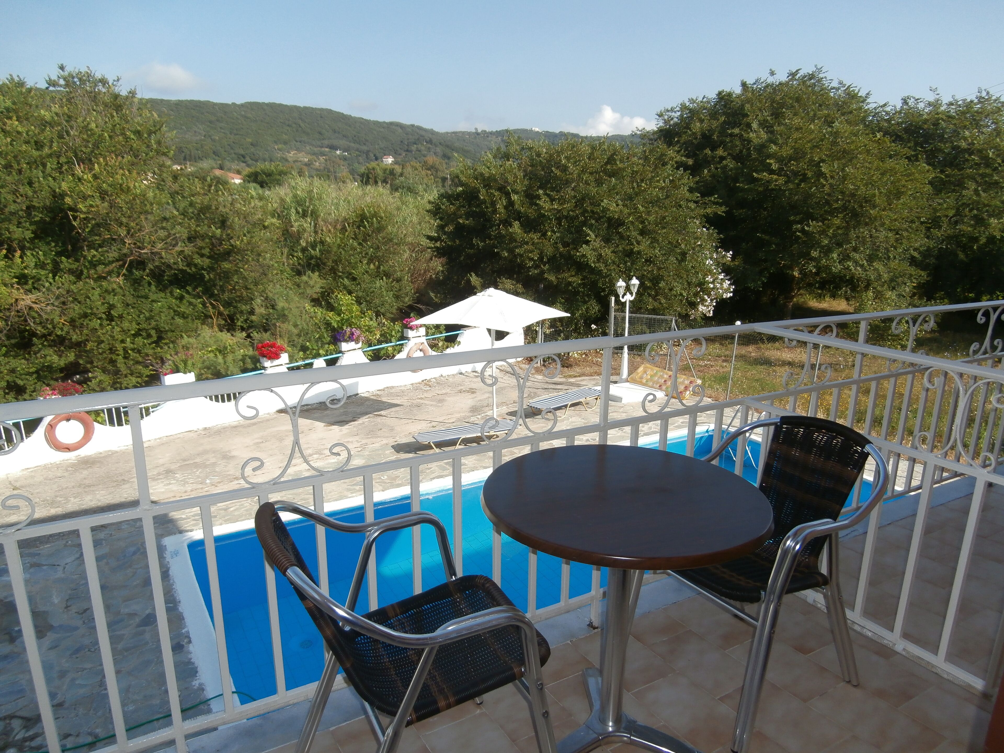 A balcony with a pool, two chairs, and a table.