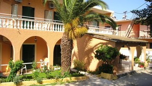 A building with a balcony, a palm tree, and a garden area. - River Studios & Apartments (Corfu)
