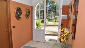 A hotel entrance with a wooden door, a marble reception desk, and a vase of sunflowers. - Albergo Ca' Vecchia (Sasso Marconi)