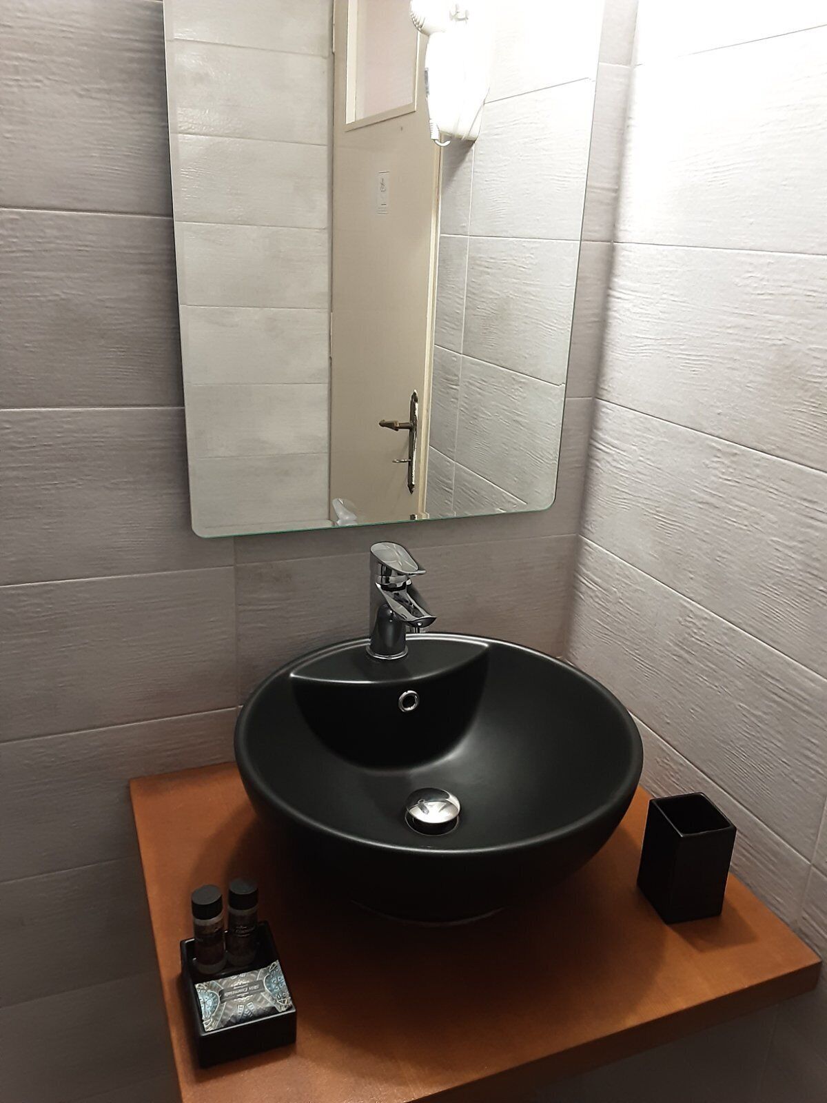 Ein Badezimmer mit schwarzem Waschbecken, einem Spiegel und einer Holzkommode.