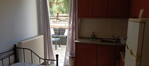 A small kitchen with a radiator, a sink, and a window with curtains. - Katerina Apartments (Kalamata)