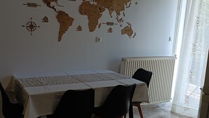 A dining area with a table set for four, a world map on the wall, and a radiator. - Katerina Apartments (Kalamata)