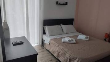 A hotel room with a bed, a bedside table, a TV, and a window with curtains.