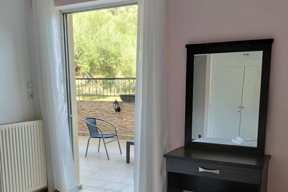 A bedroom with a bed, a dresser, a mirror, and a view of an outdoor patio.