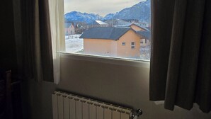 A room with a window overlooking a snowy landscape and mountains. - Cumbres Nevadas - Hostería Boutique (El Chalten)