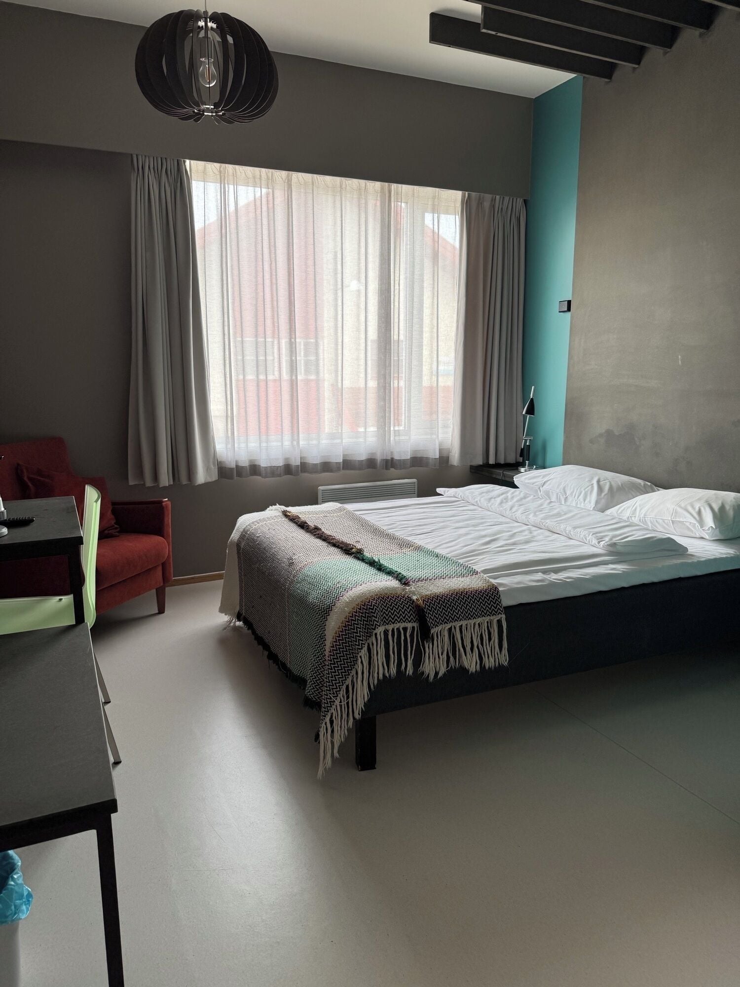 Quarto moderno com cama, escrivaninha, cadeira e janela com cortinas.