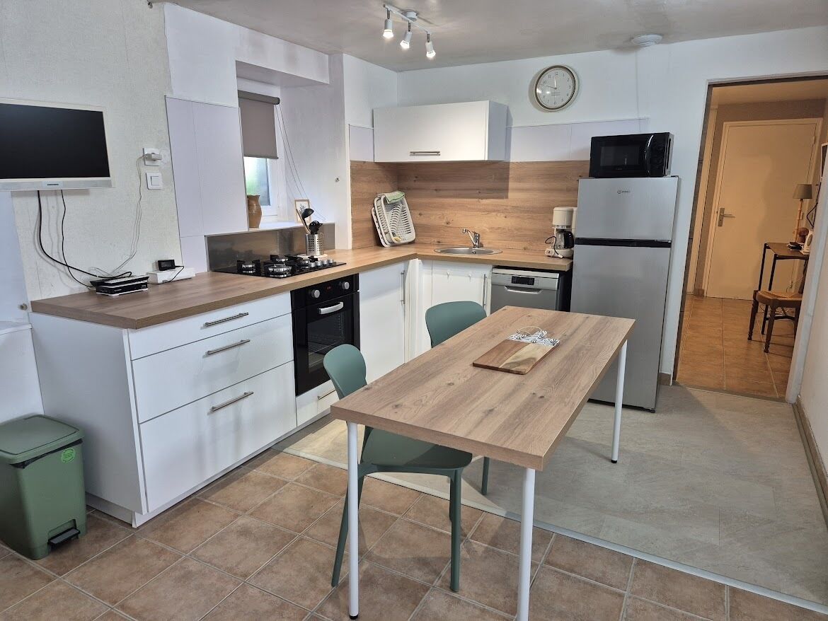 A compact kitchen with a wooden table, white cabinets, a microwave, and a refrigerator.