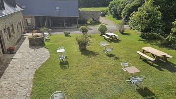 Een binnenplaats met stenen gebouwen, picknicktafels en stoelen.