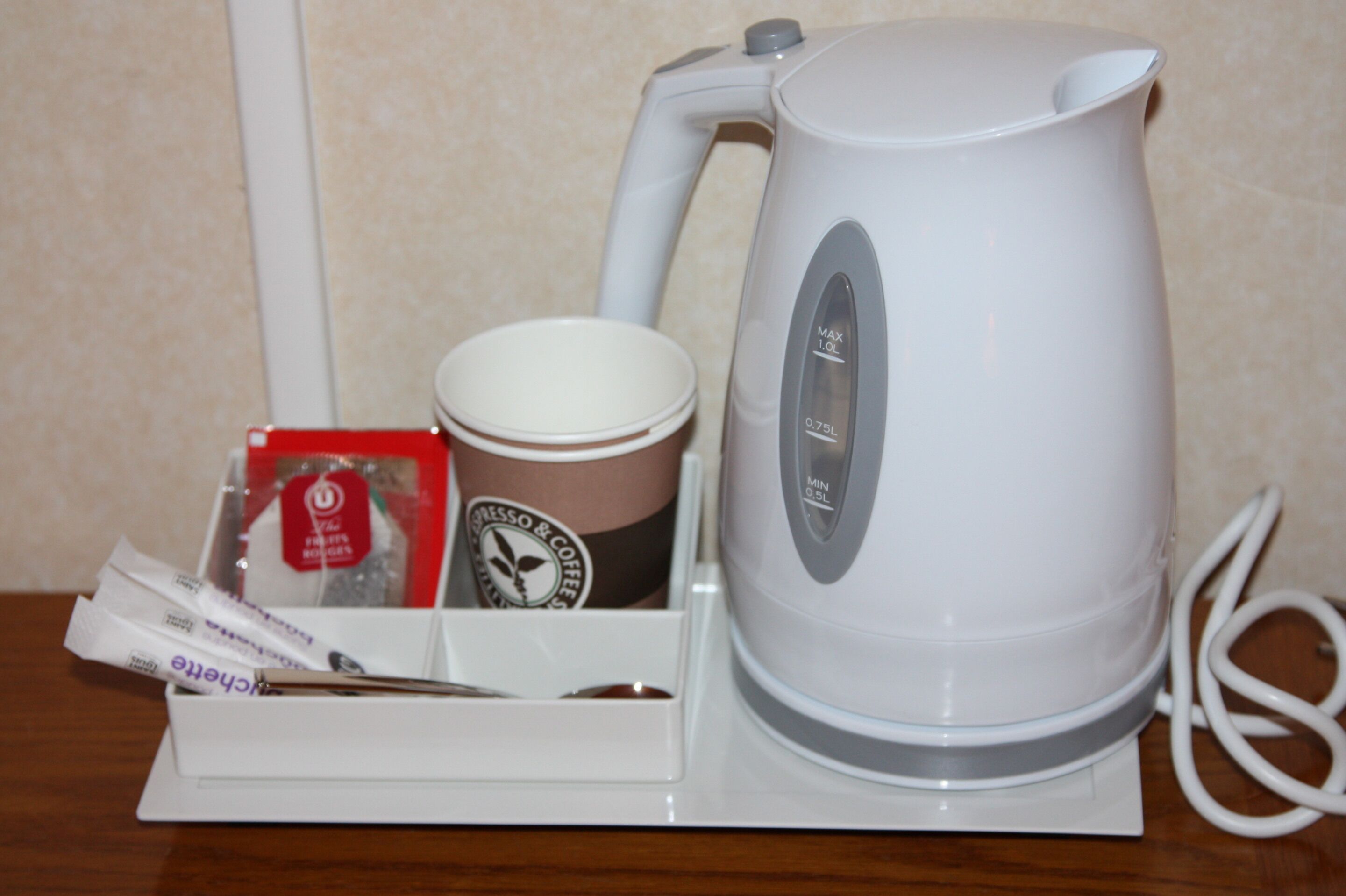 A coffee maker with a cup and a box of coffee pods on a white tray.