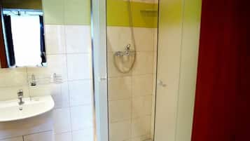 Un baño con ducha de vidrio, lavamanos e inodoro.