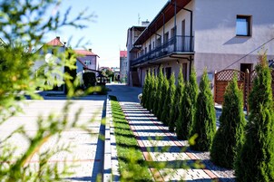 Una strada residenziale con case, un marciapiede lastricato e siepi curate.