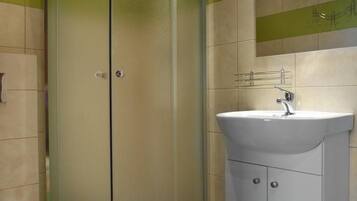 A bathroom with a glass-enclosed shower, a sink, and a toilet.