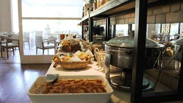 Uma área de buffet com diversos pratos, uma panela grande no fogão e uma janela com vista para o exterior.