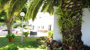 A well-maintained garden with a variety of plants and flowers, a palm tree, and a stone wall. - Hotel Arboleda (Sanxenxo)