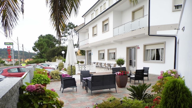 Eine Hotelterrasse mit Sitzgelegenheiten im Freien, Topfpflanzen und Blick auf die Straße.