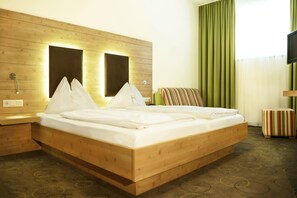 Una habitación de hotel con una cama de madera, una mesita de noche, un televisor y una cortina verde.