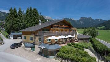 A mountain lodge with outdoor seating and a view of the surrounding mountains.