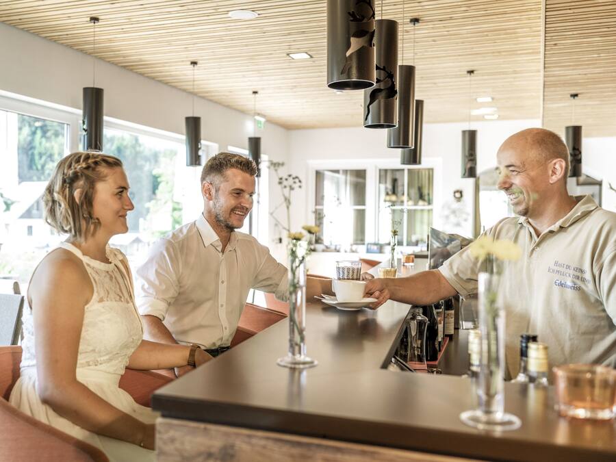 A modern bar area with a wooden ceiling, pendant lights, and a bar counter.