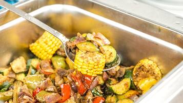 A buffet with a variety of cooked vegetables and meats.