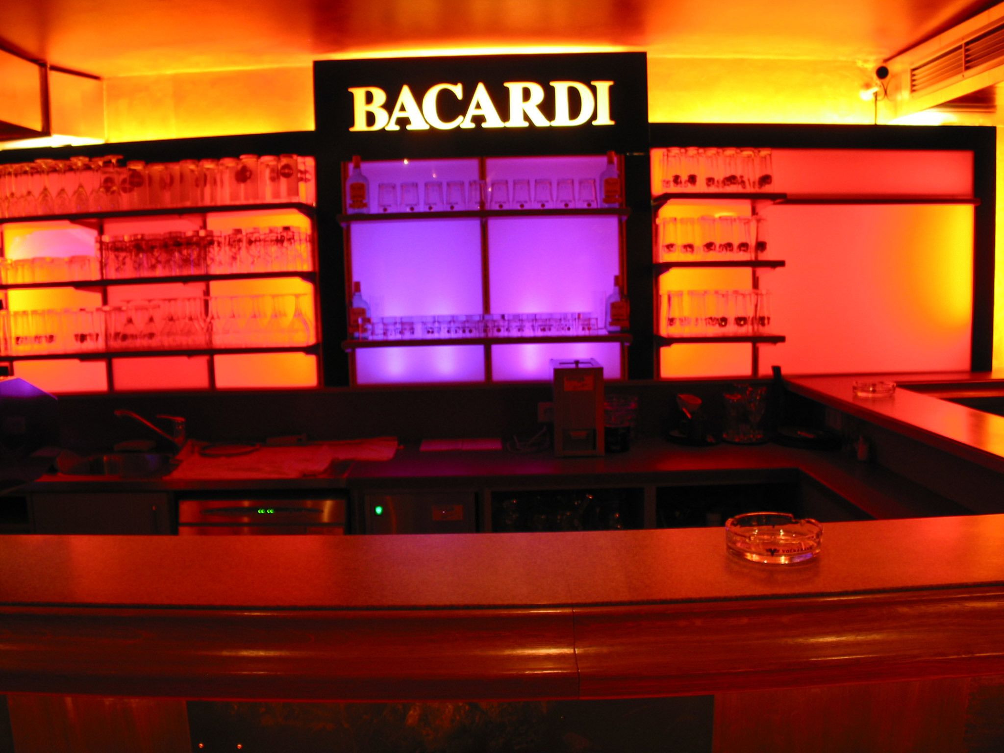 Una tienda Bacardí con estantes llenos de botellas y un cartel en la parte superior.