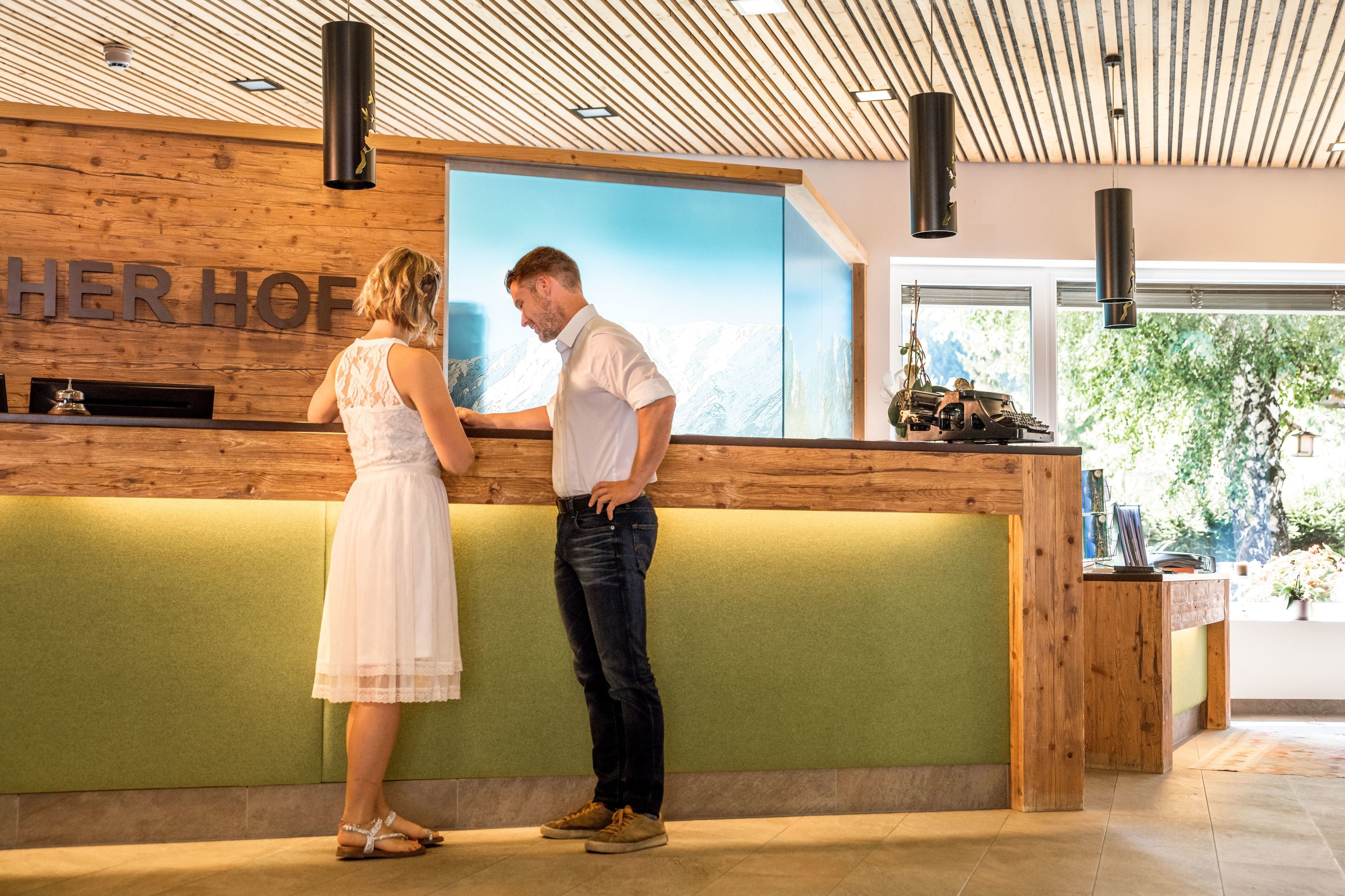 A reception desk with a wooden backdrop and a large window displaying a mountain view.