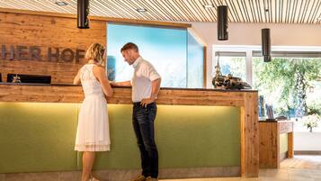 A reception desk with a wooden backdrop and a large window displaying a mountain view.