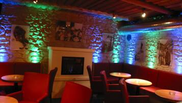 Un restaurante tenuemente iluminado con paredes de piedra, sillas tapizadas en rojo y mesas.