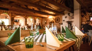 Un restaurante con mesas de madera, servilletas verdes y copas de vino.
