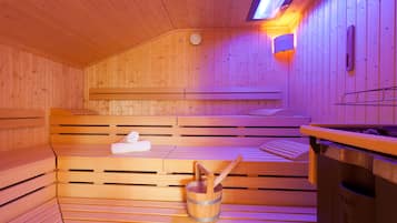 Eine Holzsauna mit Bänken, einem Eimer und einem Handtuch.